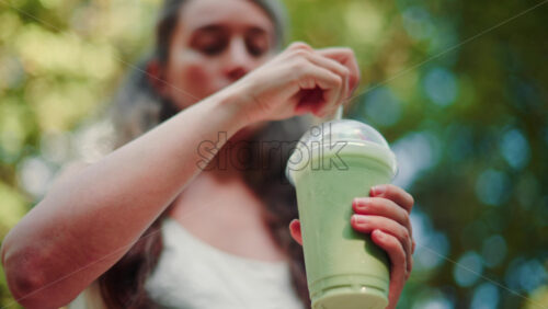 Video - Close up of woman's hand holding an iced matcha latte outdoors