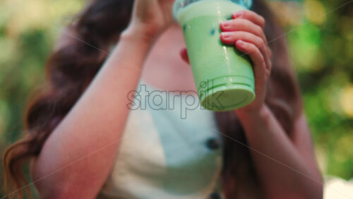 Video - Close up of woman's hand holding an iced matcha latte outdoors