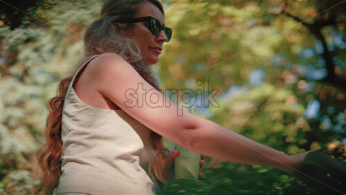Video - Close up of woman holding an iced matcha latte outdoors while pushing a stroller