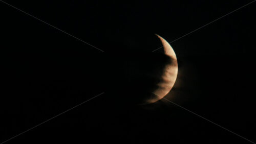Video - Illuminated crescent moon partially covered by clouds at night