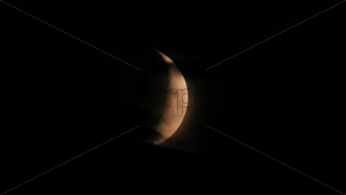 Video - Illuminated crescent moon partially covered by clouds at night