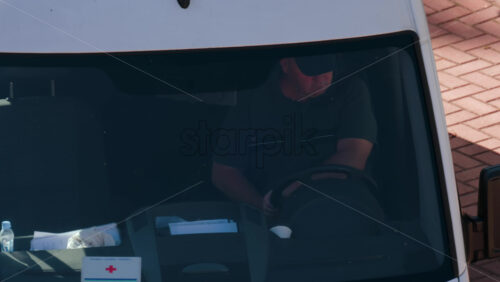 Video - Chisinau, Moldova - September 28, 2025: A man in a dark shirt driving a van under direct sunlight, viewed through the windshield