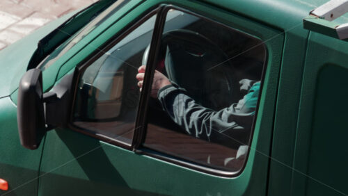 Video - Close up of a driver's hand gripping the steering wheel inside a green utility truck