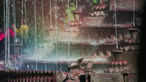 Video - View of a decorative fountain with sparkling water droplets illuminated by sunlight in a park