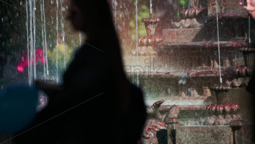 Video - View of a decorative fountain with sparkling water droplets illuminated by sunlight in a park