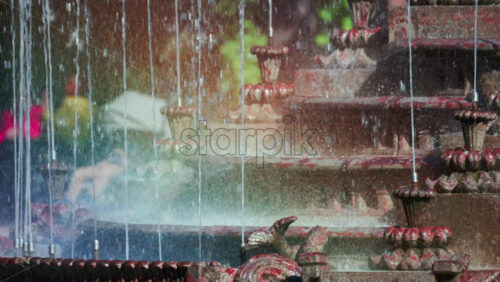 Video - View of a decorative fountain with sparkling water droplets illuminated by sunlight in a park