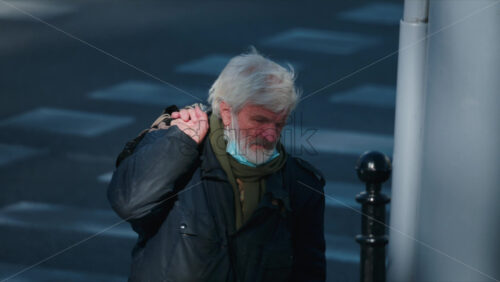Video - Chisinau, Moldova - September 30, 2025: Senior man in warm clothing carrying a bag, walking thoughtfully along a quiet city street