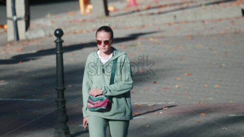 Video - Chisinau, Moldova - September 30, 2025: Stylish woman in mint green tracksuit walking outdoors on a sunny day surrounded by autumn leaves