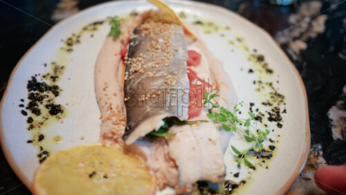 Video - Close up of a beautifully plated fish fillet with sauce, lemon slice, and herbs