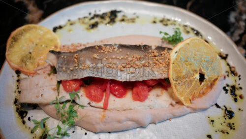 Video - Close up of a beautifully plated fish fillet with sauce, lemon slice, and herbs