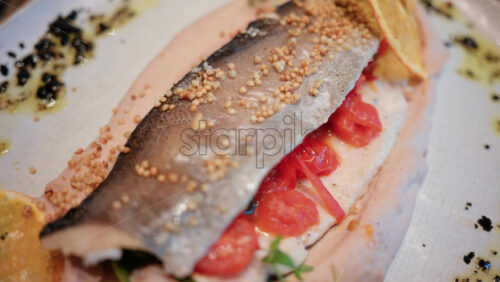 Video - Close up of a beautifully plated fish fillet with sauce, lemon slice, and herbs