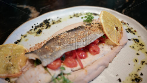 Video - Close up of a beautifully plated fish fillet with sauce, lemon slice, and herbs