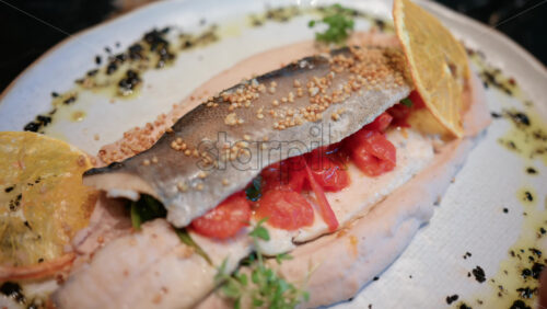Video - Close up of a beautifully plated fish fillet with sauce, lemon slice, and herbs