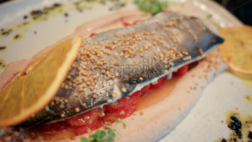 Video - Close up of a beautifully plated fish fillet with sauce, lemon slice, and herbs