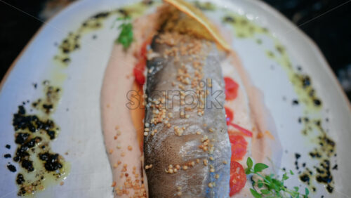 Video - Close up of a beautifully plated fish fillet with sauce, lemon slice, and herbs