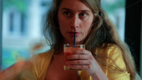 Video - Relaxed woman sipping juice through a straw in a cozy cafe