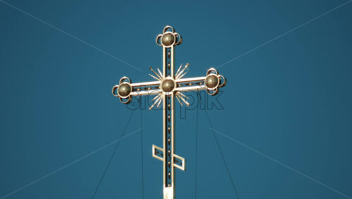 Video - Elegant metallic church cross glowing under clear blue sky