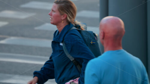 Video - Chisinau, Moldova - September 30, 2025: Blonde woman with a ponytail and blue backpack photographing the city using her smartphone than crossing the street