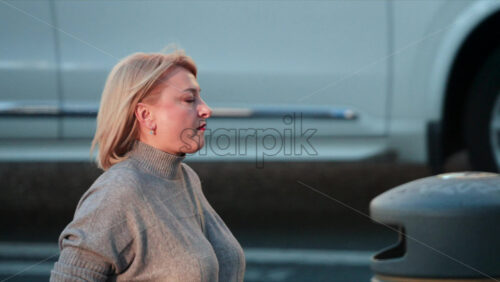 Video - Chisinau, Moldova - September 30, 2025: Blonde woman wearing a grey turtleneck walking on street in daylight