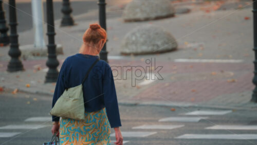 Video - Elderly woman with orange hair crossing the street in the city centre