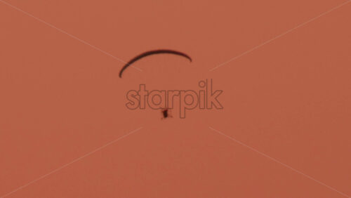 Video - A paramotor glides smoothly through a warm toned sky at sunset