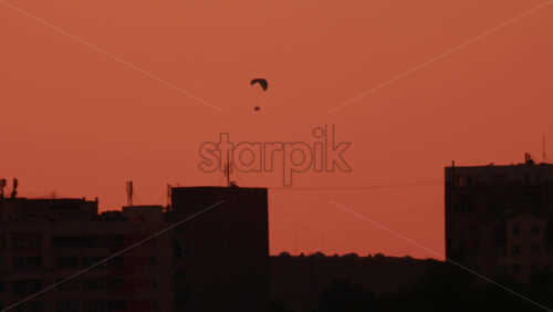 Video - A paramotor glides smoothly through a warm toned sky at sunset