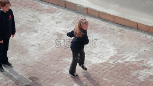Video - Chisinau, Moldova - September 30, 2025: A cheerful young girl plays badminton outside on a paved courtyard, full of joy and energy