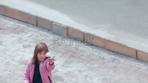 Video - Chisinau, Moldova - September 30, 2025: A young girl wearing a pink jacket holds a shuttlecock while preparing to play badminton