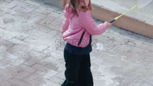 Video - Chisinau, Moldova - September 30, 2025: A young girl wearing a pink jacket holds a shuttlecock while preparing to play badminton