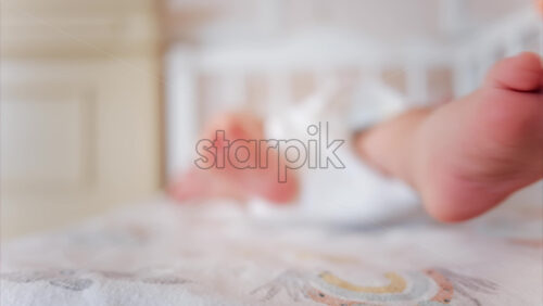 Video - Close up of baby's feet moving around on a bed