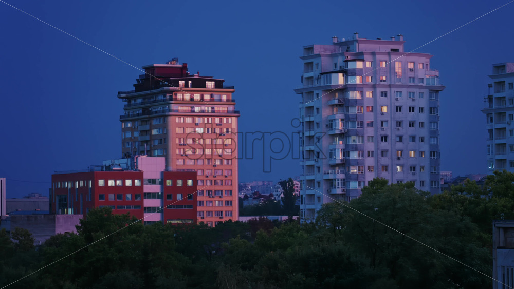 Video - High rise apartments glow under the blue evening sky with lightning
