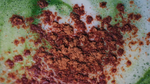 Video - Close up of matcha a latte with cinnamon sprinkled on the foam