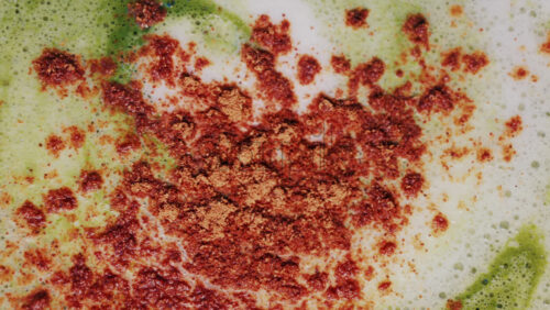 Video - Close up of matcha a latte with cinnamon sprinkled on the foam
