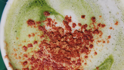 Video - Close up of matcha a latte with cinnamon sprinkled on the foam