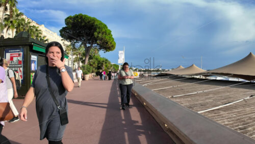 Video - Cannes, France - September 20, 2025: Famous Croisette promenade with tourists, local artists, and seaside views