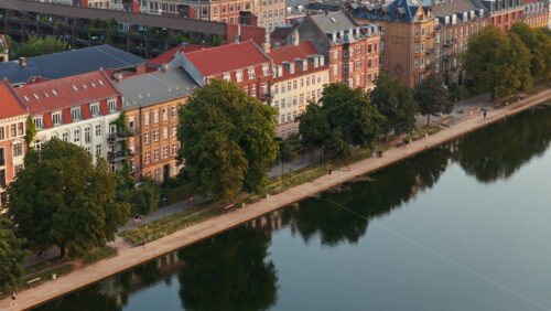 Video – Aerial drone view of the lakeside apartments along Sortedams So with people walking by the water in Copenhagen, Denmark - Starpik Stock