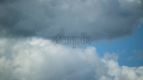 Video - Timelapse of white fluffy clouds gliding gracefully against a vibrant blue sky, creating a peaceful scene on a sunny afternoon.