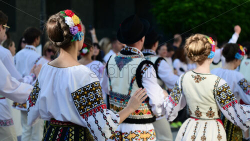 Video - A group of folk dancers showcases vibrant traditional costumes and engaging choreography at a cultural festival held in a park. Wearing traditional Moldavian costumes