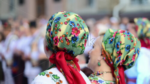 Video - Two women in beautiful floral traditional headdresses stand together, enjoying a lively cultural folk celebration, Chisinau, Moldova