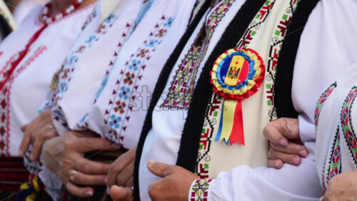 Video - People dressed in colorful traditional clothing stand together, celebrating their cultural heritage at a folk event in Chisinau. Man wearing I Love Moldova sign
