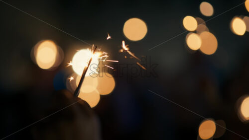 Video - People holding light up sparklers at night, celebrating. Round cinematic out of focus bokeh