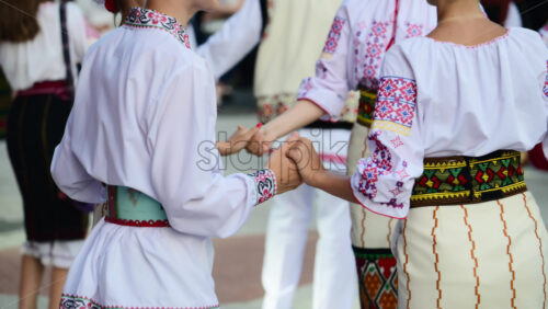 Video - Participants dressed in vibrant traditional costumes engage in a folk dance at a cultural festival. Moldavian and Romanian traditional costume