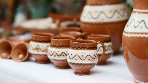 Video - Pottery display at local market showcasing handmade clay cups and pitchers for traditional drinks. Moldavian and Romanian traditional ornaments