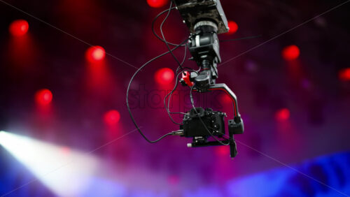 Video - Camera crane captures an aerial view of a lively concert under bright colored and flashing lights