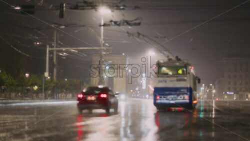 Video - Chisinau, Moldova - October 7, 2025: Rain pours down on city streets as vehicles and trolleybus move cautiously through the waterlogged roads