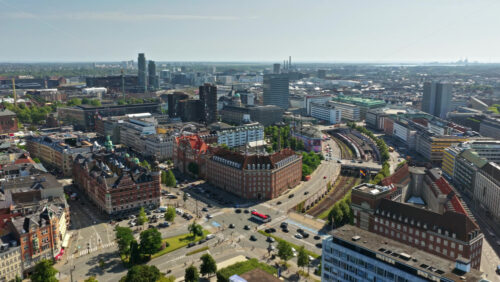 Video - Aerial drone view of a bustling intersection showing cars, buses, cyclists, and red S-train passing through the city center