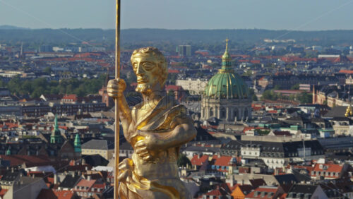 Video - Aerial drone view of the golden statue atop a sphere on the Church of Our Saviour overlooking the Copenhagen skyline, with Frederik's Church dome in the background in Denmark