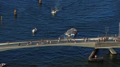 Video - Copenhagen, Denmark - August 6, 2025: Aerial drone view of boats and a canal tour passing under Inderhavnsbroen pedestrian and bicycle bridge
