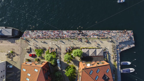 Video - Aerial drone view of people sunbathing and swimming along the lively promenade by the harbor at the Islands Brygge waterfront, Copenhagen, Denmark