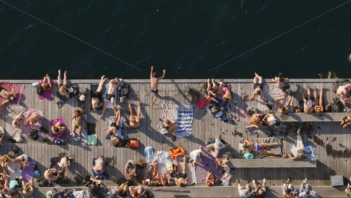 Video - Aerial drone view of people sunbathing and swimming along the lively promenade by the harbor at the Islands Brygge waterfront